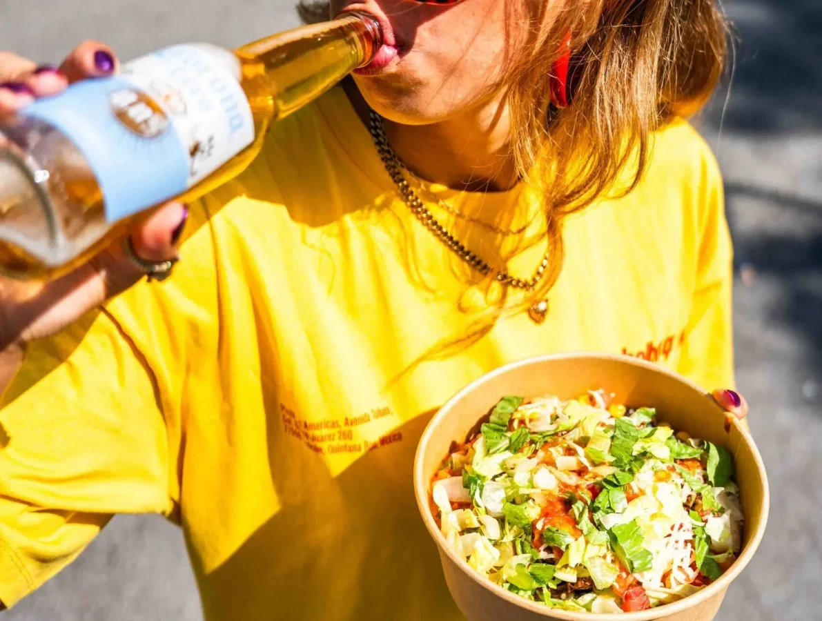A guest enjoying a Salsa Shop bowl and a cold drink in the sun